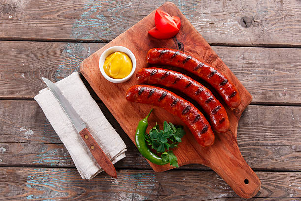 grilled sausage on a wooden board with sauce and vegetables - chorizo stockfoto's en -beelden