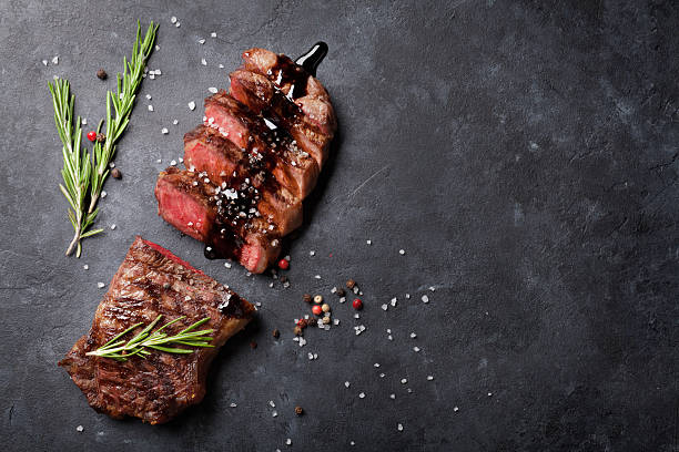 Grilled striploin steak Grilled striploin sliced steak with salt and pepper over stone table. Top view with copy space rosemary photos stock pictures, royalty-free photos & images