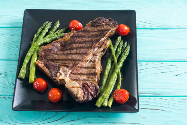 Grilled T-bone steak with asparagus and cherry tomatoes stock photo