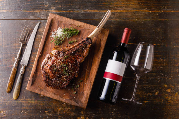 Grilled Tomahawk Steak on bone and bottle of Red wine on wooden background stock photo