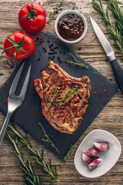 Grilled veal chop with vegetables on rustic table. Top view stock photo