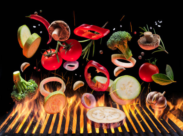 Grilled vegetables and mushrooms in motion falling down on open grill. Conceptual photo of barbeque cooking process. stock photo