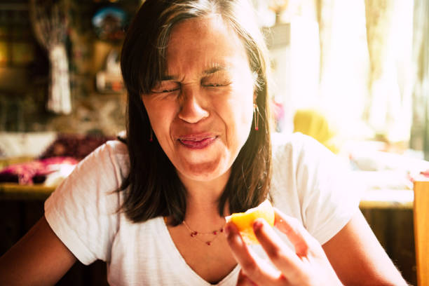 Grimace Woman eat lemon and make a grimace sour taste stock pictures, royalty-free photos & images