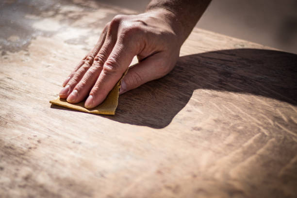 Gritty weathered man's hand sanding a wooden surface stock photo