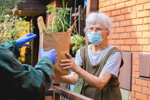 grocery delivery to senior woman during pandemic food delivered to elderly person during epidemic lockdown isolation food donation stock pictures, royalty-free photos & images