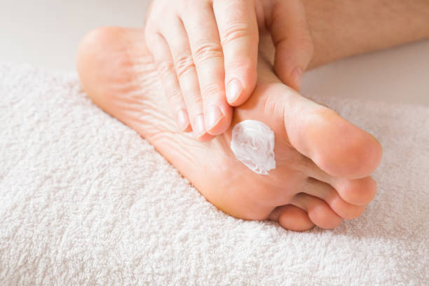 Groomed, young man's hand applying feet moisturizing cream. Barefoot on the white towel. Cares about clean and soft legs skin. Healthcare concept. Groomed, young man's hand applying feet moisturizing cream. Barefoot on the white towel. Cares about clean and soft legs skin. Healthcare concept. man pedicure stock pictures, royalty-free photos & images