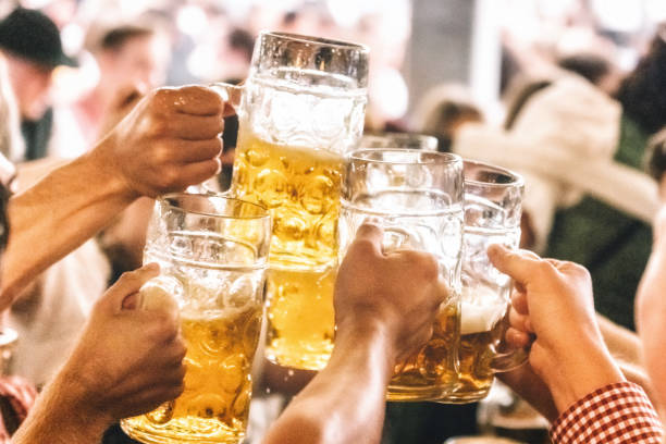 group of people clinking beer glasses  in beer hall at oktoberfest in munich