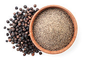 istock Ground black pepper in a wooden bowl and peppercorns on a white background, isolated. Top view 1301622377