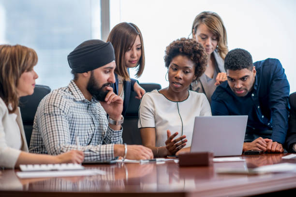 Group analysis of digital data A diverse group of business people gather around a laptop in a modern office and discuss what they see. islam stock pictures, royalty-free photos & images