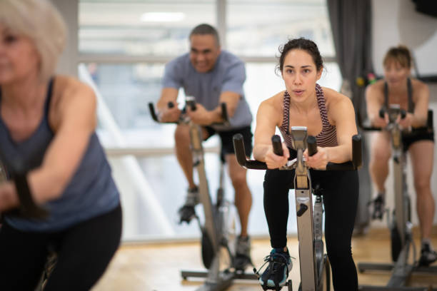 Group exercise class A group of multi-ethnic friends spend time working out one afternoon. They are bonding while taking a exercise class together. spinning stock pictures, royalty-free photos & images