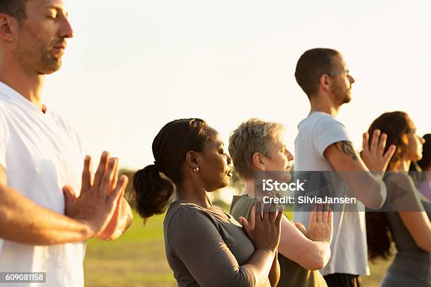 Group exercising Yoga outdoors at sunset