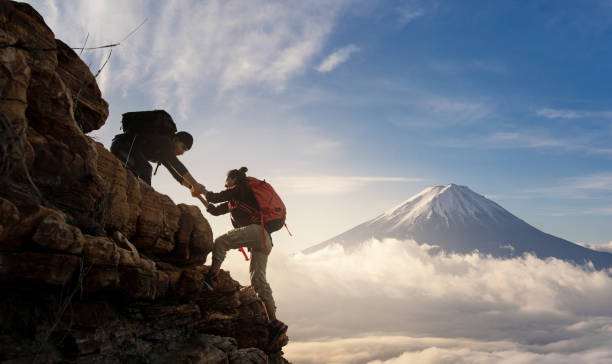 아시아의 그룹 하이킹은 햇빛을 가진 산에서 서로의 실루엣을 돕습니다. - 등정 뉴스 사진 이미지