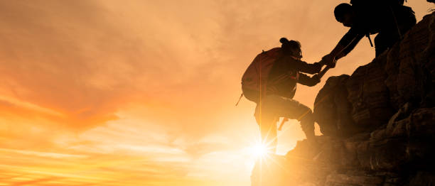 아시아 하이킹 그룹은 햇빛이 들어오는 산에서 서로 실루엣을 돕습니다. - 등정 뉴스 사진 이미지