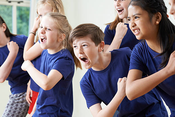 group of children enjoying drama class together - acteren stockfoto's en -beelden