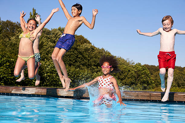 Group Of Children Jumping Into Outdoor Swimming Pool  little girls in bathing suits stock pictures, royalty-free photos & images