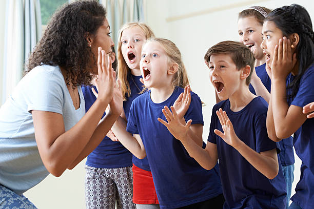 group of children with teacher enjoying drama class together - acteren stockfoto's en -beelden