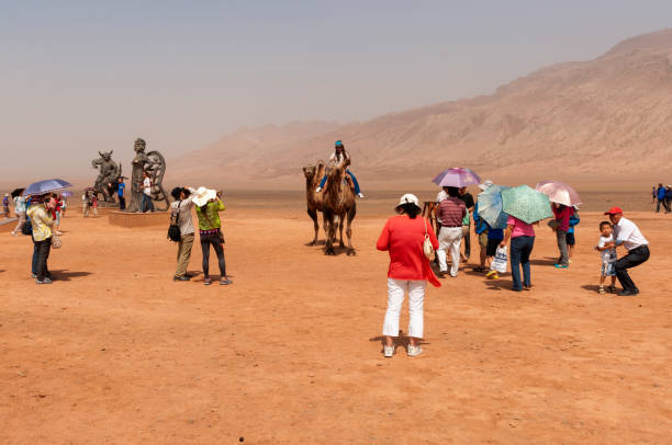 Group of Chinese tourists taking pictures near the Flaming Mountains, Xinjiang Flaming Mountains, Xinjiang, China - August 12, 2012: Group of Chinese tourists taking pictures near the Flaming Mountains, Xinjiang, China tien shan mountains stock pictures, royalty-free photos & images