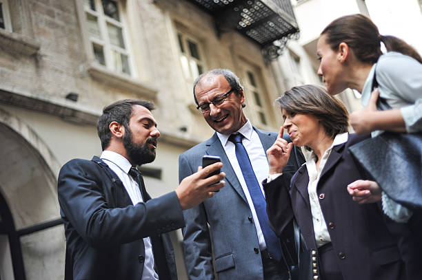 Group of colleagues looking at a smartphone stock photo