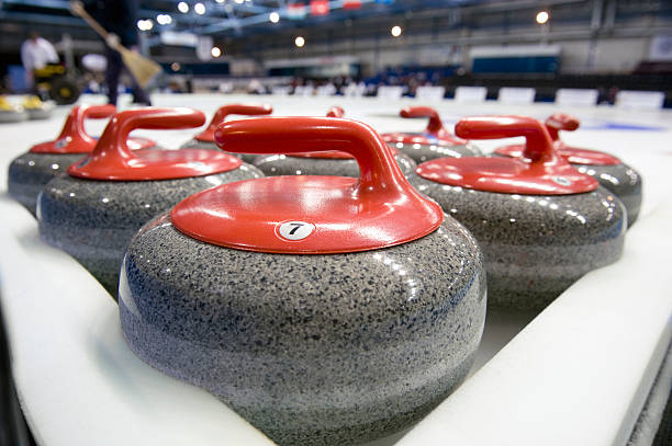 a group of curling rocks in focus on an ice rink - curling stockfoto's en -beelden