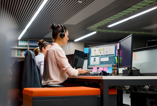 Group of customer service representatives working at a call center using headsets and their computers. **DESIGN ON SCREEN BELONGS TO US**