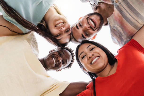 Group of diverse friends hugging in circle - Happy people having fun outdoor - Main focus in gay man face stock photo