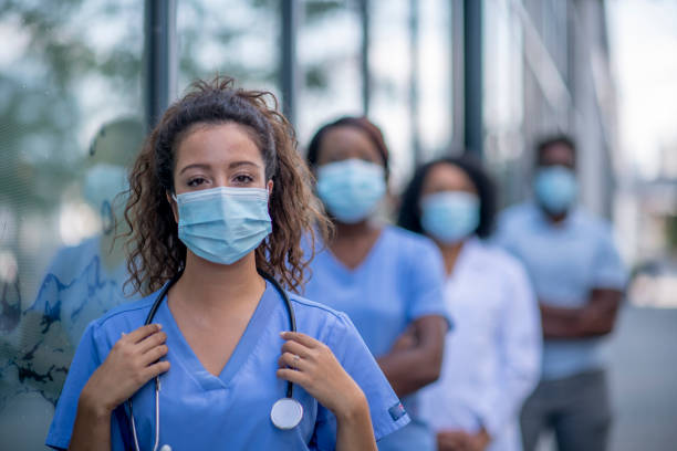 Group of doctors outside Diverse group of medical professionals outside the hospital wearing protective face masks. nurse photos stock pictures, royalty-free photos & images