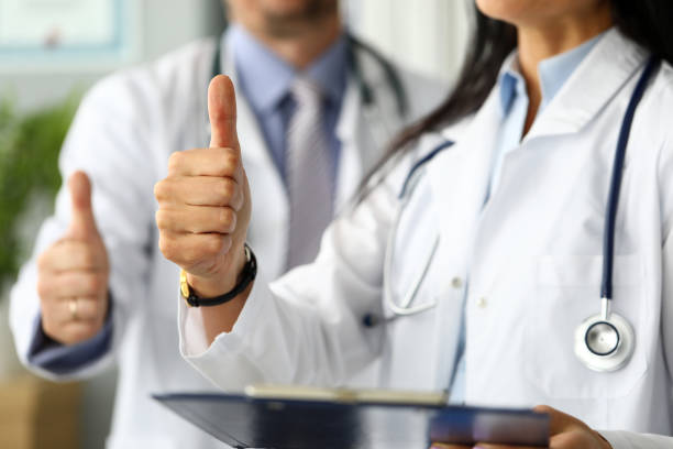 Group of doctors standing in row showing thumb up symbol Group of doctors standing in row showing thumb up symbol as public opinion expression for good treatment closeup general view stock pictures, royalty-free photos & images
