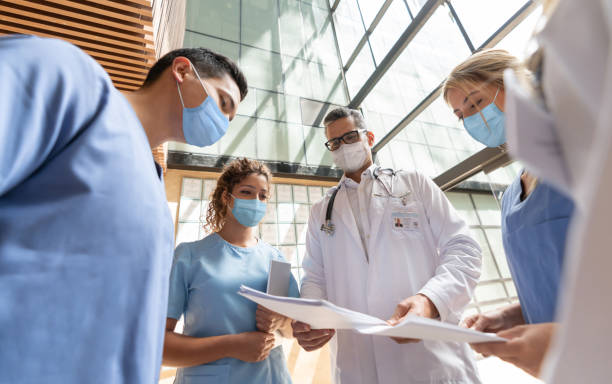 Group of doctors talking at the hospital and wearing facemasks Group of Latin American doctors talking at the hospital and wearing facemasks during the COVID-19 pandemic - healthcare and medicine concepts medical occupation stock pictures, royalty-free photos & images