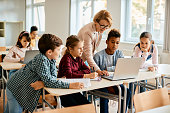 istock Group of elementary students having computer class with their teacher in the classroom. 1358014313