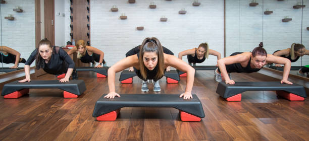 group of fitness women doing push ups on aerobic stepper in gym. - steps imagens e fotografias de stock