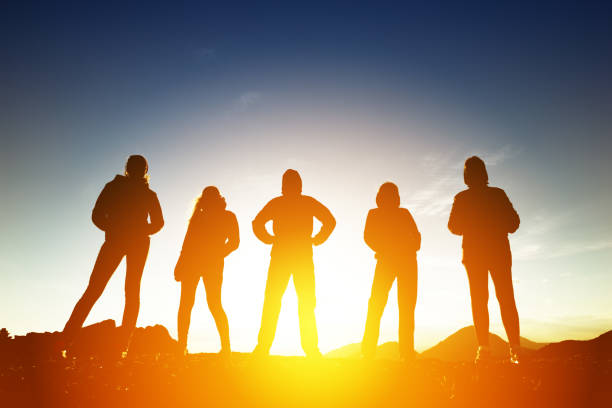 Group of five peoples in silhouettes at sunset Group of five peoples silhouettes in sunset light back lit stock pictures, royalty-free photos & images