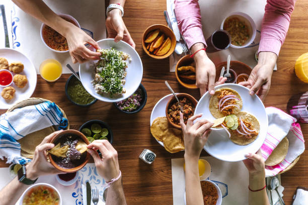group of Friend eating Mexican Tacos and traditional food, snacks and peoples hands over table, top view. Mexican cuisine stock photo