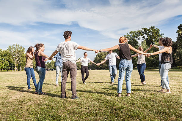 Group of friends at park holding hands. stock photo