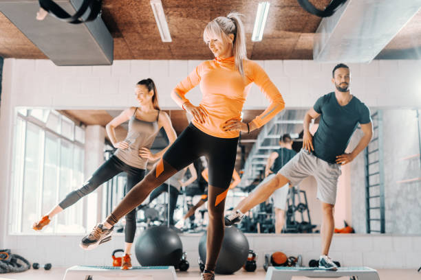 Group of friends doing fitness exercises for legs in gym. In background their mirror reflection. Group of friends doing fitness exercises for legs in gym. In background their mirror reflection. manufactured object stock pictures, royalty-free photos & images