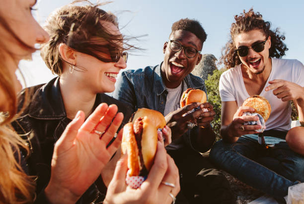 groupe d’amis de manger le hamburger sur le dessus de la montagne - eating burger photos et images de collection