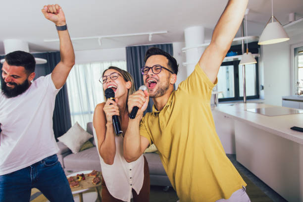 Group of  friends having fun at home. They are drinking beer and having karaoke. stock photo