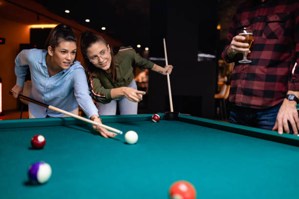A group of friends having fun playing billiards at a downtown pub. stock photo
