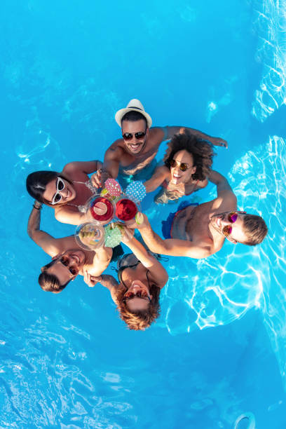Group of friends having party in pool stock photo