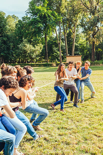 Group of friends playing tug of rope in park stock photo