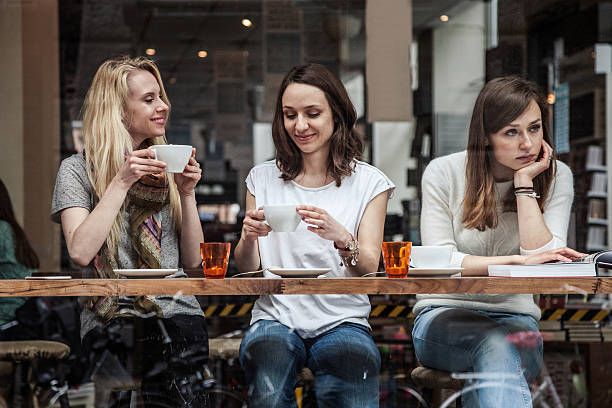 Group of friends relaxing at cafe in Scandinavia Group of women seated at a cafe's window relaxing during a cold afternoon in Scandinavia, Copenhagen. cafe culture stock pictures, royalty-free photos & images