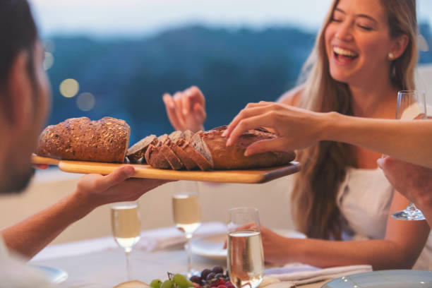 Group of friends sharing a loaf of bread at a dinner party. stock photo
