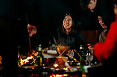キャンプの火の周りに座って、冬の夜に食べ物や飲み物を楽しむ友人のグループ