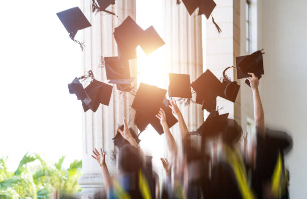 Group of graduates throwing graduation hats in the air stock photo