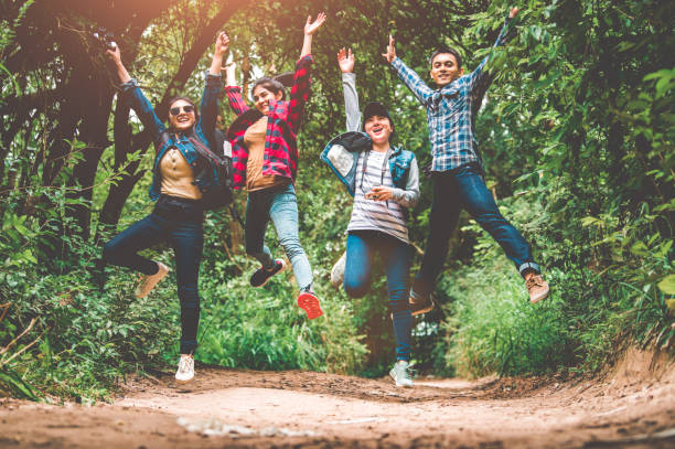 groep van gelukkige aziatische tiener avontuur reiziger trekkers groep springen samen in berg op outdoor forest achtergrond. jonge wandelaar vrienden die elkaar ondersteunen als survival team reizen en succes - klimbos stockfoto's en -beelden