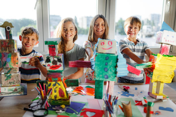 Group of happy kids making robot toys from cardboard stock photo