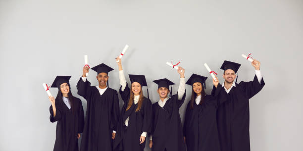 Group of happy multiethnic college or university graduates holding up their diplomas stock photo