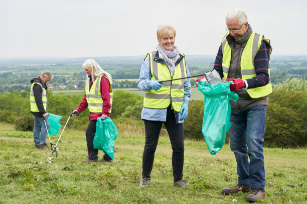 Group Of Helpful Seniors Collecting Litter In Countryside stock photo