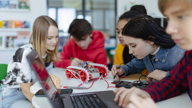 Group of high school students building and programming electric toys and robots at robotics classroom stock photo