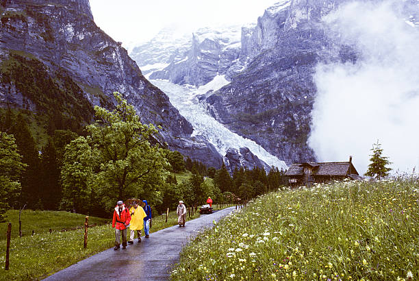 Hikers Pass by the Glacier on a Foggy, Rainy Day Grindelwald, Bern Canton, Switzerland - July 10, 1978: A group of hikers in the fog and rain passes by a glacier on the way to Grosse Scheidegg. jeff goulden switzerland stock pictures, royalty-free photos & images