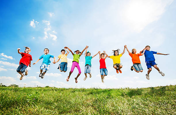 group of kids having fun while jumping against the sky. - menselijke ledematen stockfoto's en -beelden
